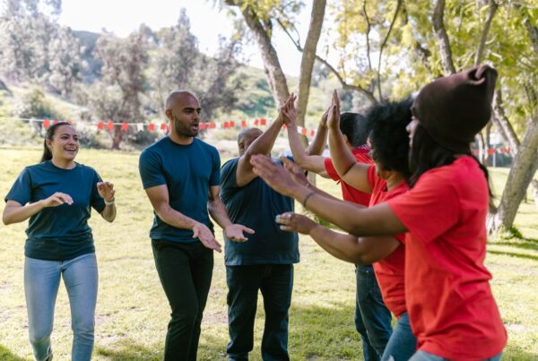 Colleagues giving each other high fives during an outdoor team building day.